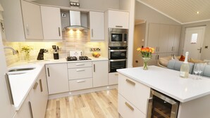 A modern kitchen with white cabinetry, a built-in oven, a microwave, and a gas stove. - 8 Waterside Wood (Windermere)