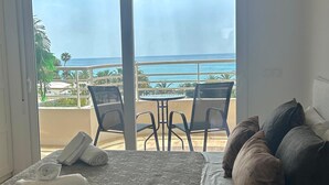 A room with a bed, a table with chairs, and a view of the ocean.