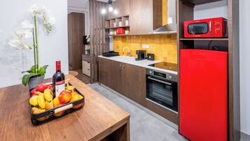 Cocina moderna con armarios de madera, un refrigerador rojo, un microondas y una cesta de frutas sobre la encimera.