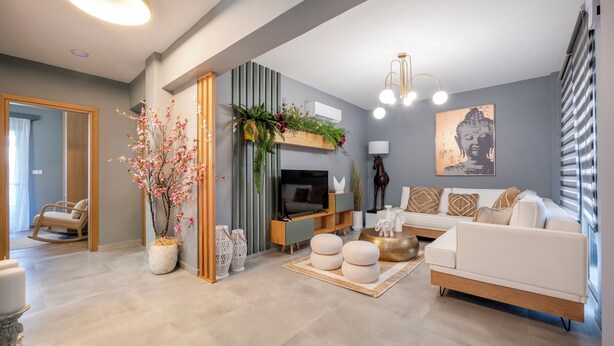 A modern living room with a sofa, TV, decorative plants, and a Buddha painting.