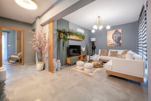 Una sala de estar moderna con sofá, televisor, plantas decorativas y un cuadro de Buda.