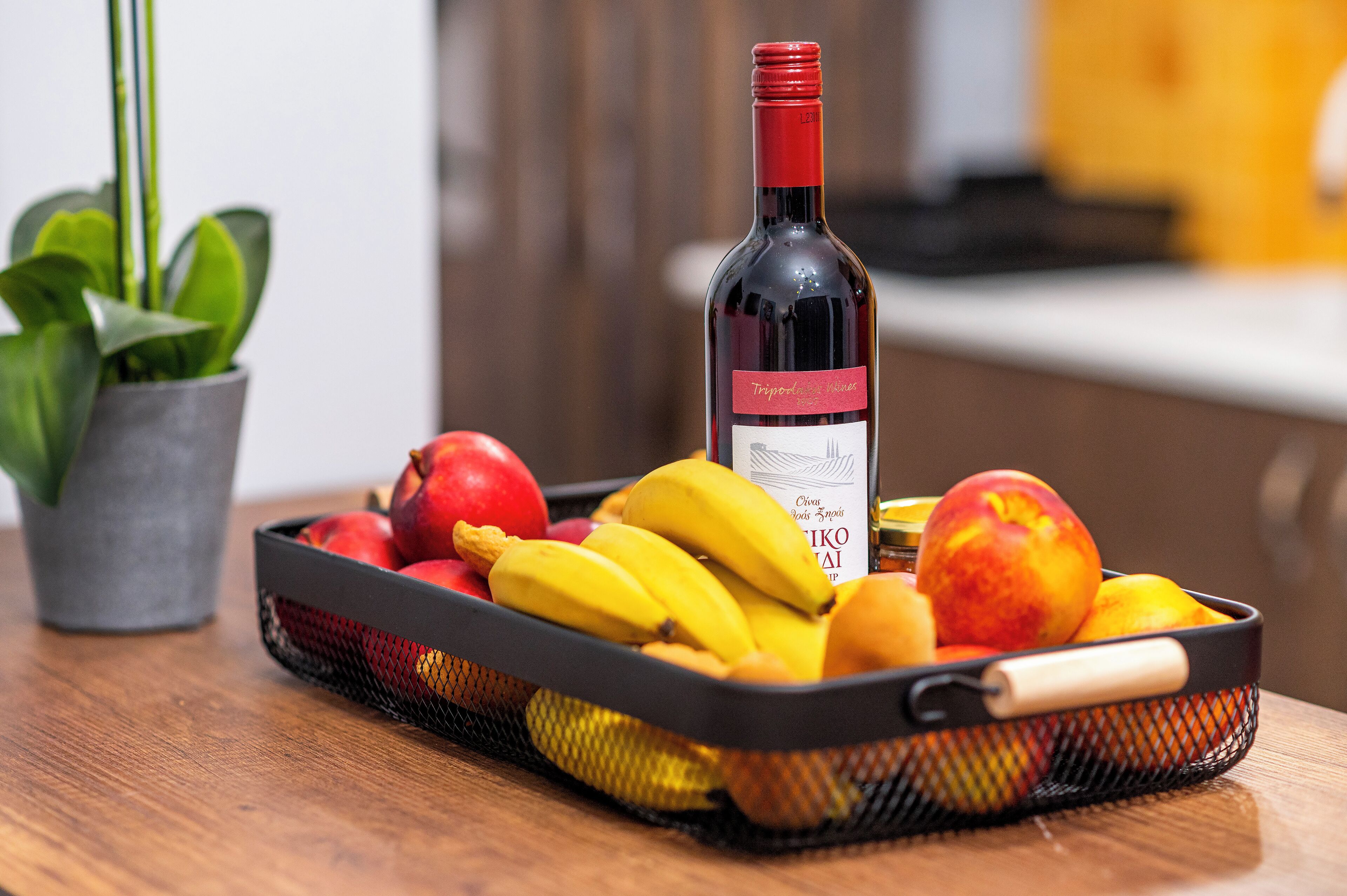 A table with a basket of fruits and a bottle of wine.