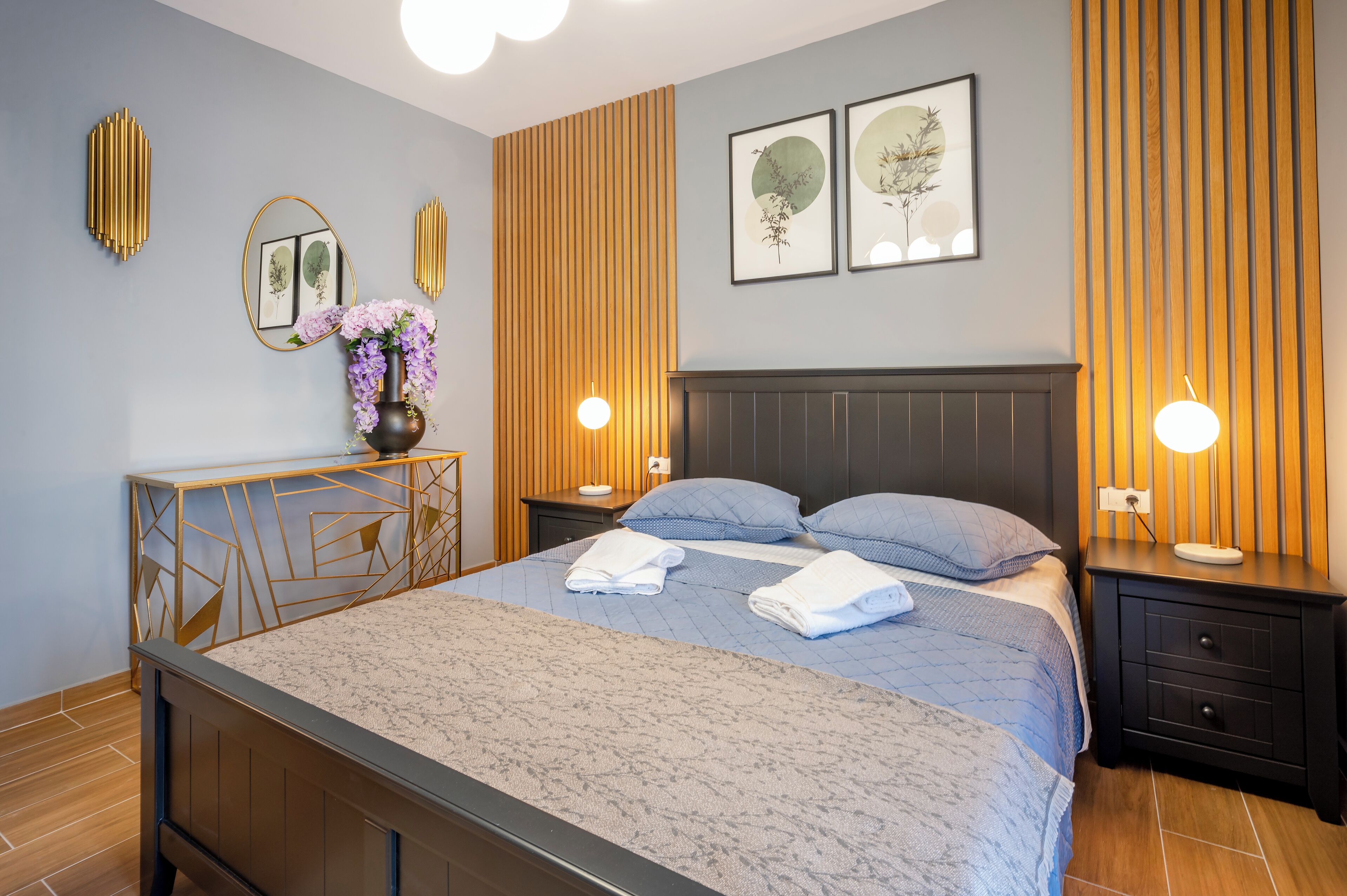 Une chambre moderne comprenant un lit, des tables de chevet, une commode et des luminaires fixés au mur.
