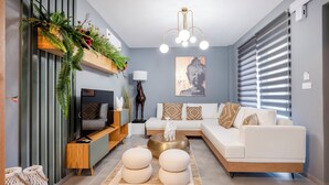 A modern living room with a white sofa, a round coffee table, and a decorative plant shelf.