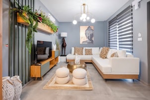 Una sala de estar moderna con un sofá blanco, una mesa de centro redonda y una estantería decorativa con plantas.