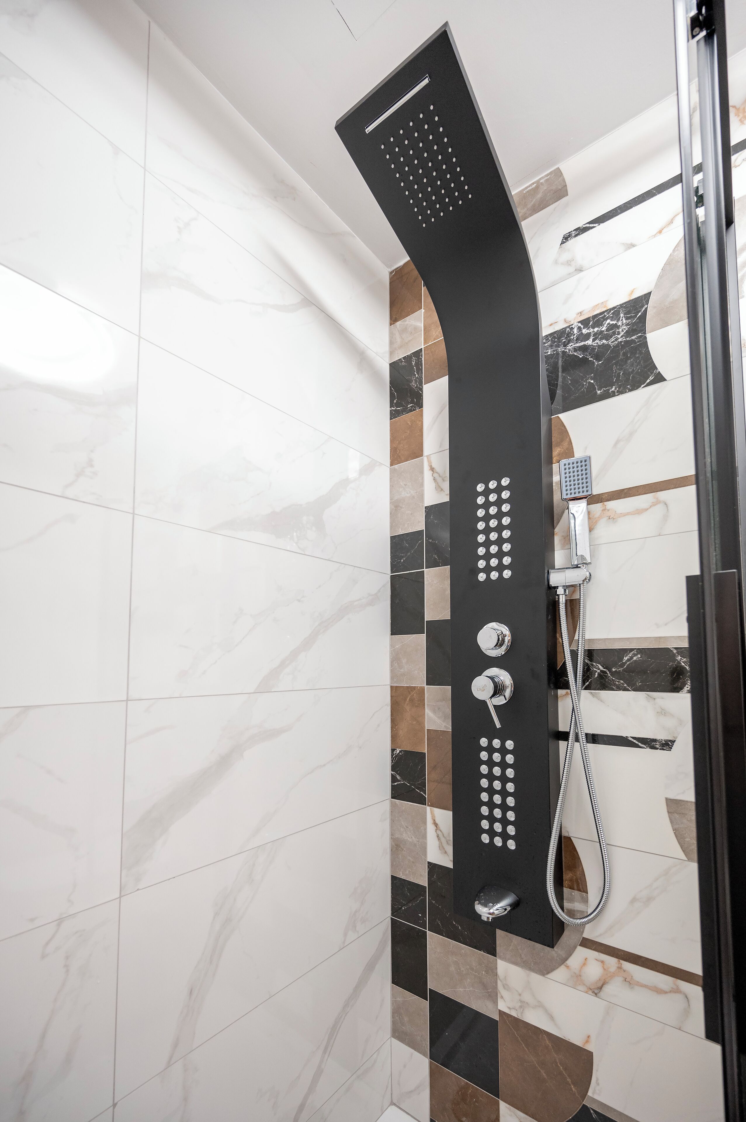 A modern shower with a curved design, a handheld showerhead, and a handheld faucet.