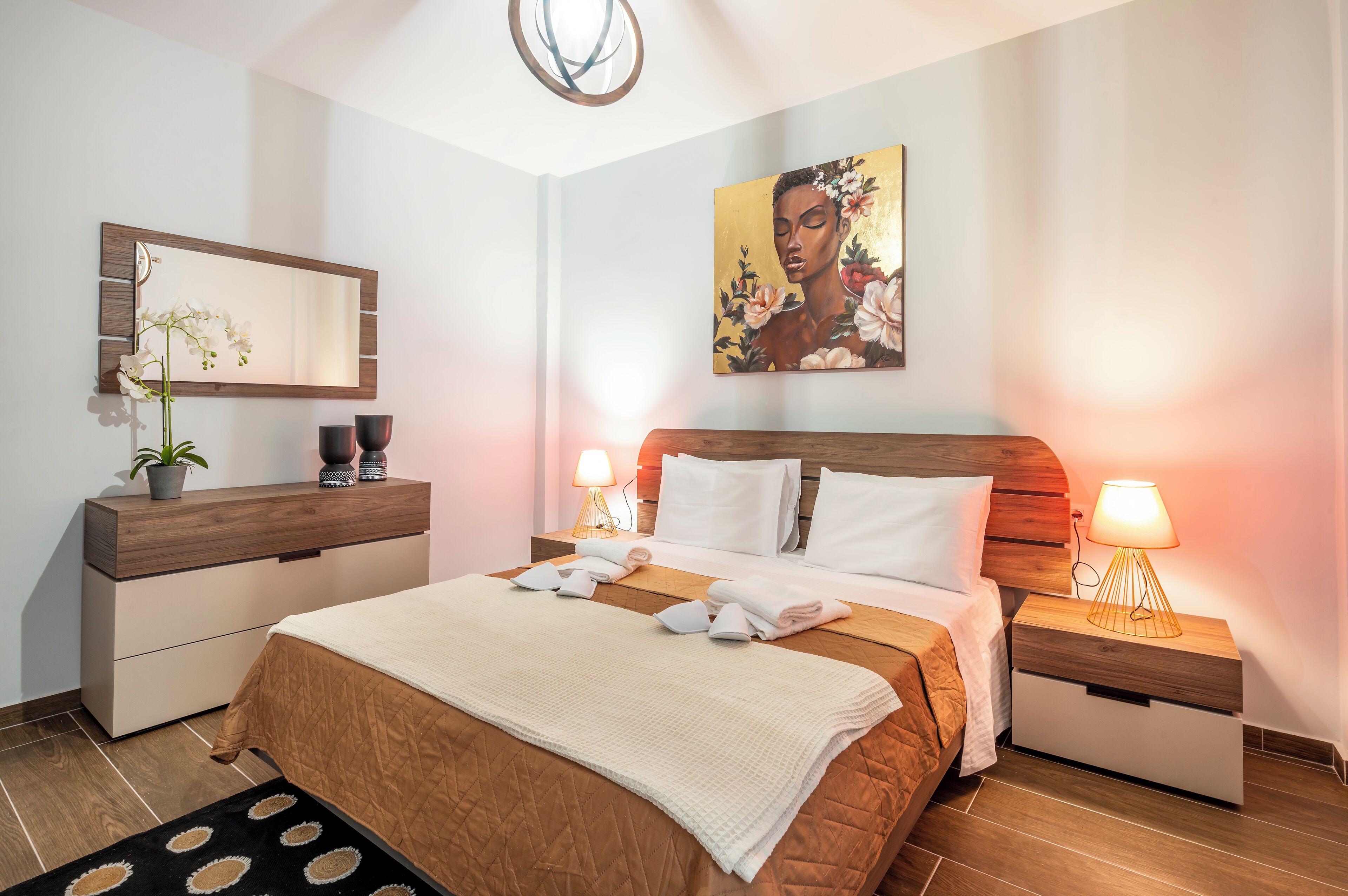 Une chambre à coucher comprenant un lit, des tables de chevet, une commode, un miroir, un tableau et une plante en pot.