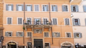 A multi-story building with a row of shops on the ground floor, including 'NUVOLARI' and 'GINO'. - Corso View apartment (Rome)