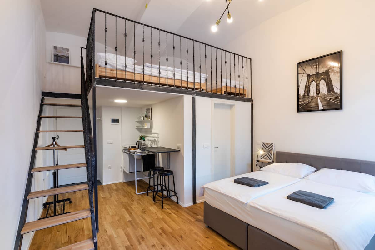 Habitació senzilla amb lliteres, petita cuina i escala.