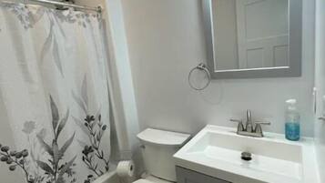 Un baño con cortina de ducha, inodoro, lavabo y armario.