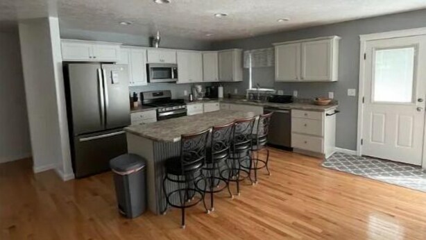 A modern kitchen with white cabinets, stainless steel appliances, and a wooden floor. - Entire house in the quiet town of Fort Shaw (Fort Shaw)