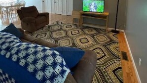 A living room with a sofa, a patterned rug, a television, and a floor lamp. - Entire house in the quiet town of Fort Shaw (Fort Shaw)