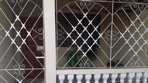 A building facade with decorative metal window grills and a white balustrade. - Hostal Bella Mar CIENFUEGOS (Cienfuegos)