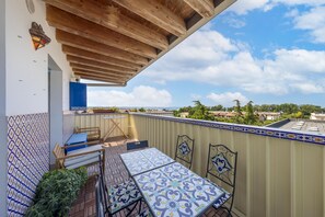 Ein Balkon mit Fliesenboden, einem Tisch, Stühlen und Blick auf die Stadtlandschaft.