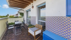 Eine Terrassengruppe im Freien mit einer Holzbank, einem Tisch und Stühlen sowie einer Wand mit Muster.