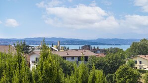 A residential area with houses, trees, and a lake in the background. - Condominio San Francesco 53 by Wonderful Italy (Desenzano del Garda)