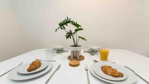 Una tavola per la colazione con croissant, un bicchiere di succo d'arancia e una pianta in vaso.