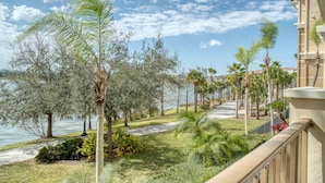A balcony with a view of a landscaped area featuring palm trees and a pathway leading to a body of water. - Vista Cay Luxury Lakeview 3 Bedroom Condo 3087 (Orlando)