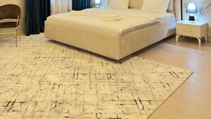 A modern bedroom with a large bed, a chandelier, and a marble wall. - Nur Makon (Tashkent)