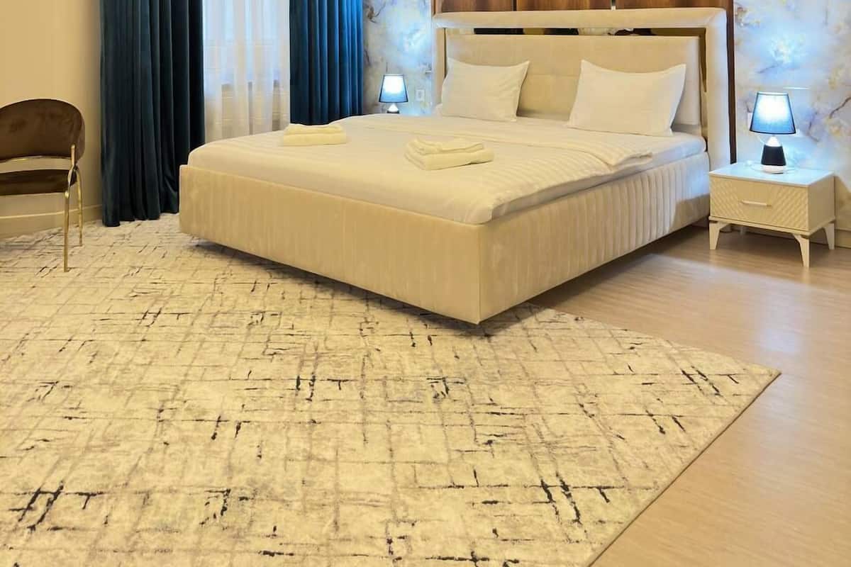 Un dormitorio moderno con una cama grande, una araña y una pared de mármol.