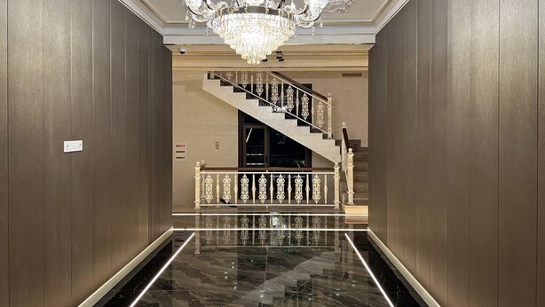 A grand hallway with a marble floor, a chandelier, and a staircase with ornate railings. - Nur Makon (Tashkent)