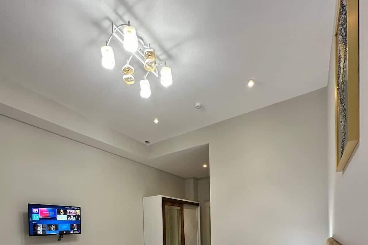 Habitación de hotel con dos camas, un escritorio con silla, televisor y espejo.