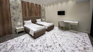 A modern hotel room with two beds, a desk, and a TV. - Nur Makon (Tashkent)