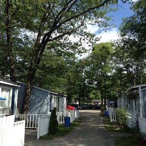Une rangée de maisons mobiles, avec des clôtures blanches et des arbres en arrière-plan.