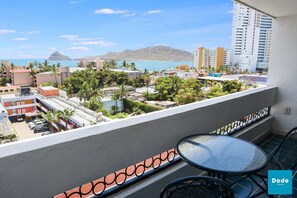 A balcony with a table and chairs, overlooking a cityscape with buildings and a mountain in the distance. - Las Palmas (Mazatlán)