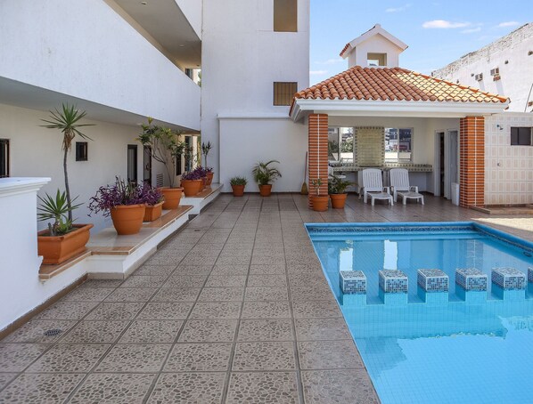 A swimming pool with tiled flooring, potted plants, and outdoor seating. - Las Palmas (Mazatlán)