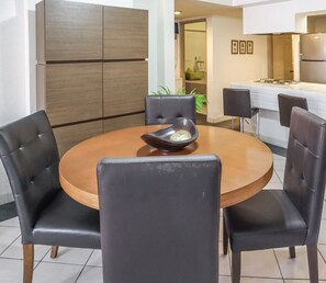 A dining area with a round table, black upholstered chairs, and a wooden cabinet in the background. - Las Palmas (Mazatlán)
