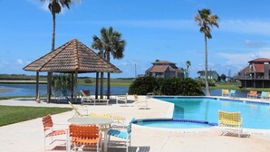 A pool area with lounge chairs, a gazebo, and palm trees. - Oceanview, Updated, Wi-Fi , Pool.  Family Unit for 6 -  Must be 25+ to rent. (Matagorda)