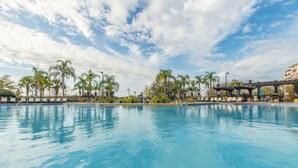 A swimming pool with lounge chairs and palm trees.