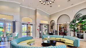 A spacious lobby with a curved seating area, large windows, and a visible exit sign.