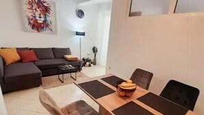 Una sala moderna con sofá, una mesa de comedor con sillas y un elemento decorativo en la pared.