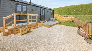 A modern building with a gravel patio, wooden deck, and a fenced garden area. - The Liddel Dutch Barn - UK44465 (Saughtree, near Kielder)