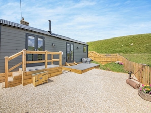 A modern building with a gravel patio, wooden deck, and a fenced garden area. - The Liddel Dutch Barn - UK44465 (Saughtree, near Kielder)
