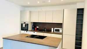 A modern kitchen with a central island, built-in appliances, and a minimalist design. - 2 bedrooms with Terrace and Parking (Luxembourg City)