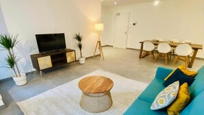 A modern living room with a sofa, coffee table, TV, dining table, chairs, and potted plants. - 2 bedrooms with Terrace and Parking (Luxembourg City)