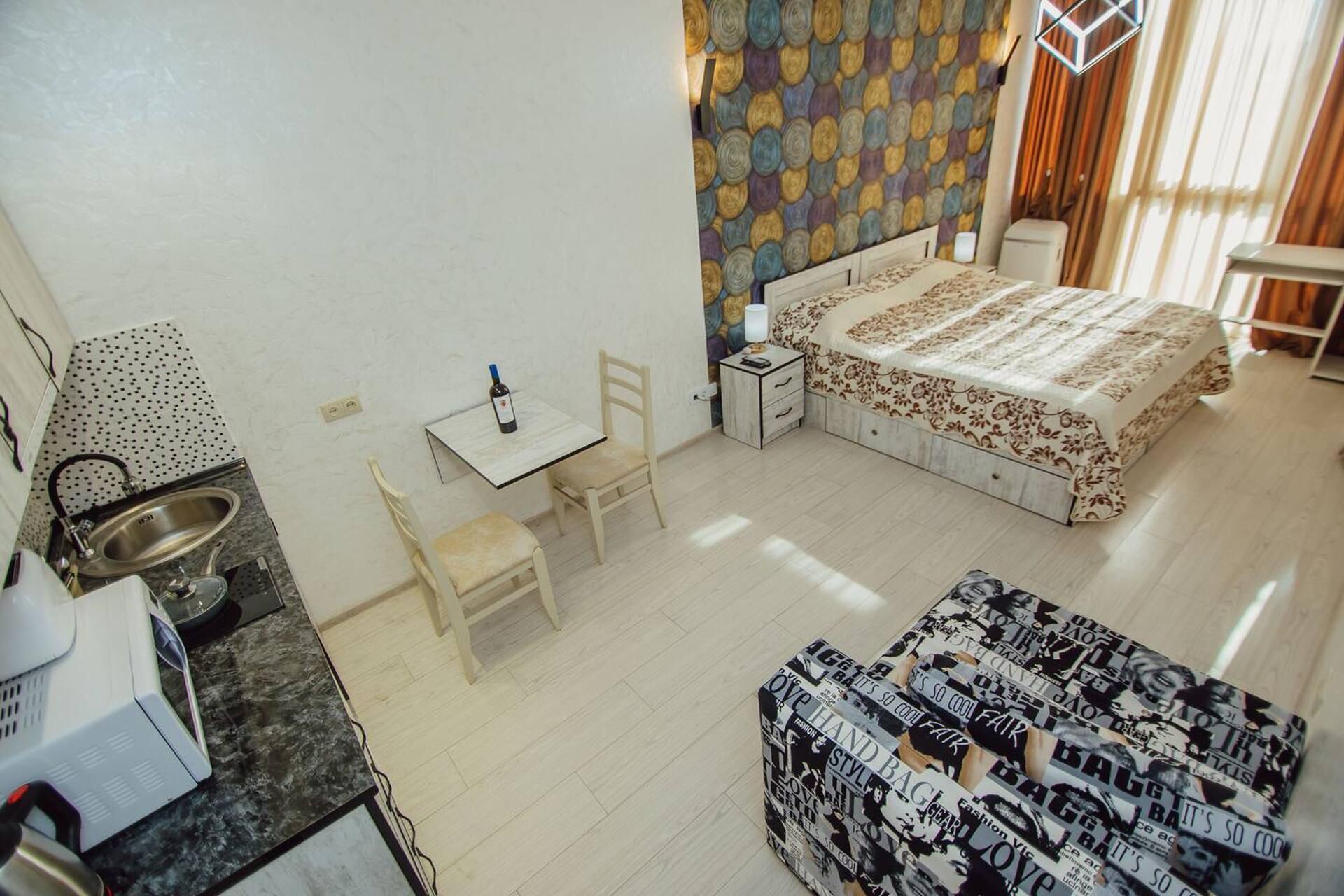 Una camera d'albergo compatta con un letto, un tavolino, una sedia, un divano e angolo cottura.
