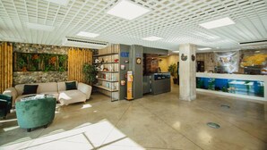 A spacious lobby with a modern ceiling design, a reception desk, and a seating area with a sofa and ottoman. - Lovely Studio in Batumi With Rooftop in Building (Batumi)