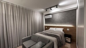 A modern hotel room with a large bed, a seating area, and an air conditioning unit. - Is Moema (São Paulo)