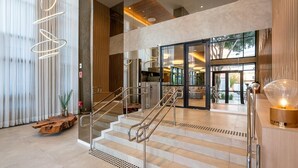 A modern hotel lobby with a staircase, a reception desk, and a view into the dining area. - Is Moema (São Paulo)