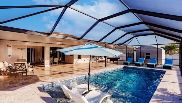 Piscina com estrutura de cobertura geométrica, espreguiçadeiras e área de pátio.