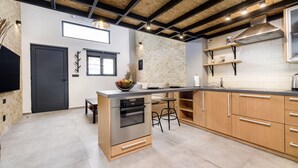 A modern kitchen with a central island, stainless steel appliances, and wooden cabinets. - Loft 1 (Kos)