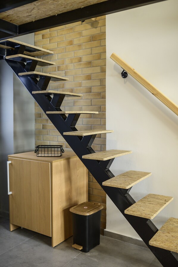 Un escalier en colimaçon avec une finition en bois, une structure en métal noir et un mur de briques en arrière-plan.
