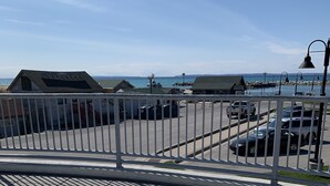 Näkymä merenrannalle, jossa on valkoisia Adirondack-tyylisiä tuoleja, historiallinen rakennus, jonka kyltissä lukee ”Historiallinen Fishtown”, ja pysäköintialue, jossa on autoja.