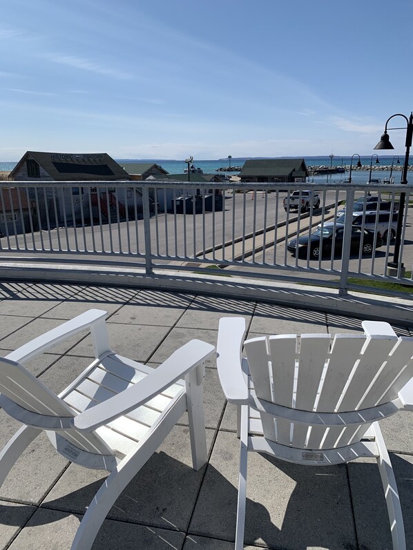 A waterfront view with white Adirondack chairs, a historic building labeled 'Historic Fishtown', and a parking area with cars. - Classic Cottage in the Heart of Leland (Leland)