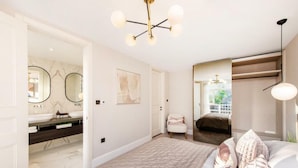 Une chambre à coucher avec un grand lit, une table de chevet, un miroir et un luminaire au plafond.