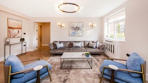 Un salon spacieux avec un grand canapé, deux fauteuils, une table basse et un lustre moderne.